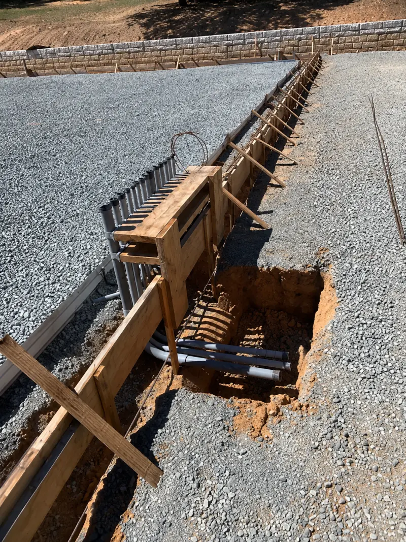 Concrete block retaining wall with drainage trench and piping